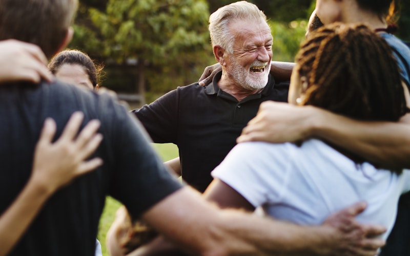 Group of older adults hugging and smiling in circle