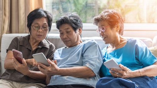 Three people sitting on couch looking at phone