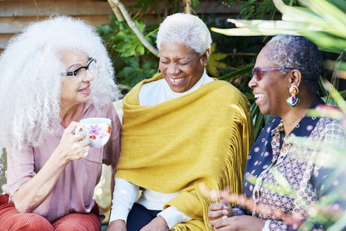 three older women laughing outside together