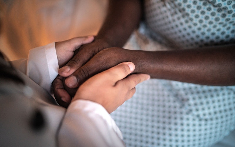 Doctor holding the hands of a patient in a hospital gown