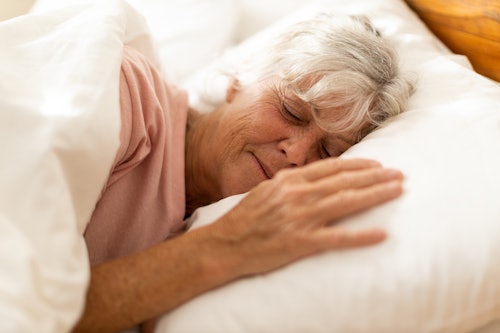 older woman sleeping peacefully in white sheets