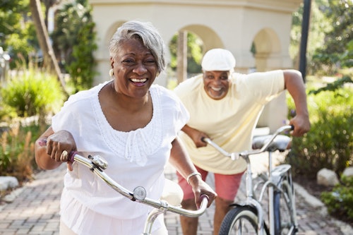 An older couple smiling while riding bikes outdoors