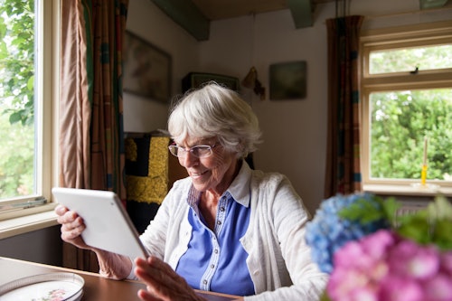 older woman reviewing paperwork on table with flowers