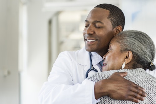 Doctor hugging elderly woman in hospital