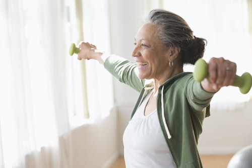 woman lifting green weights in home