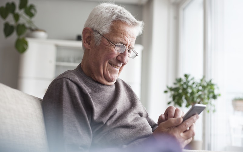 Man sitting on couch smiling at phone screen
