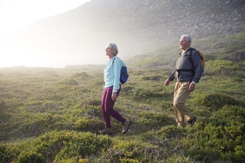 older couple hiking in green grass outside