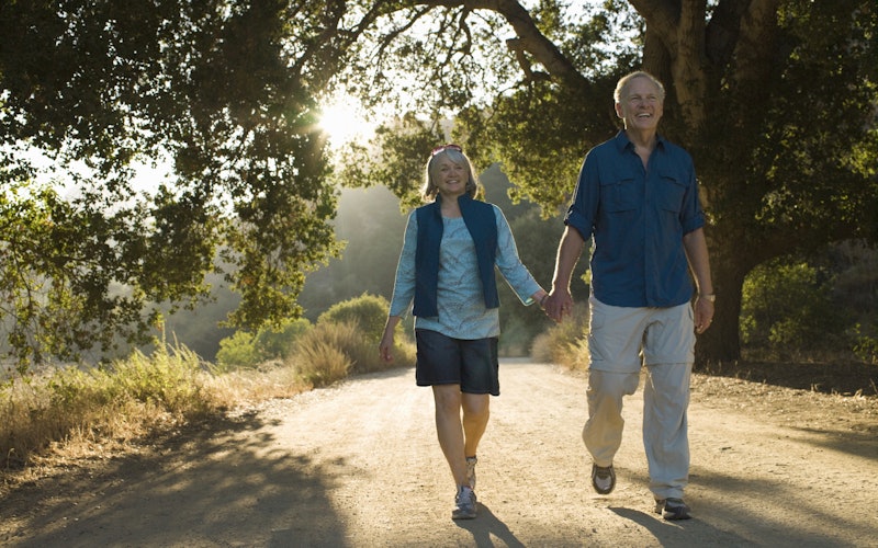 older couple walking on a trail in forest