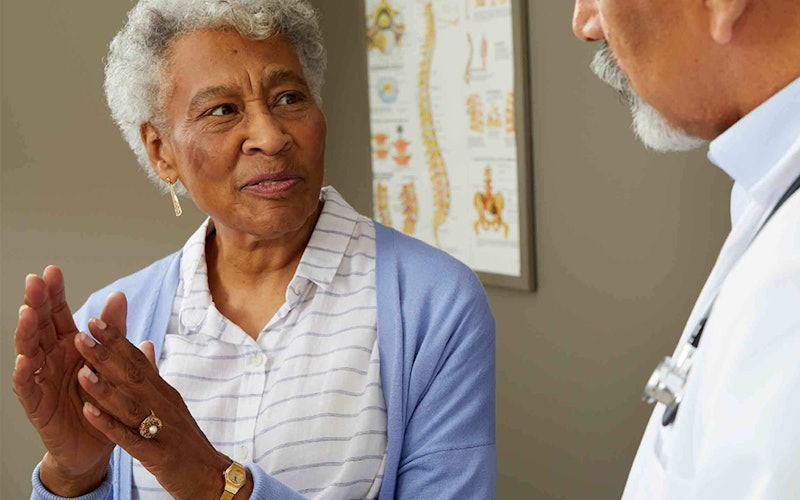 An older woman looking at and talking to a doctor.