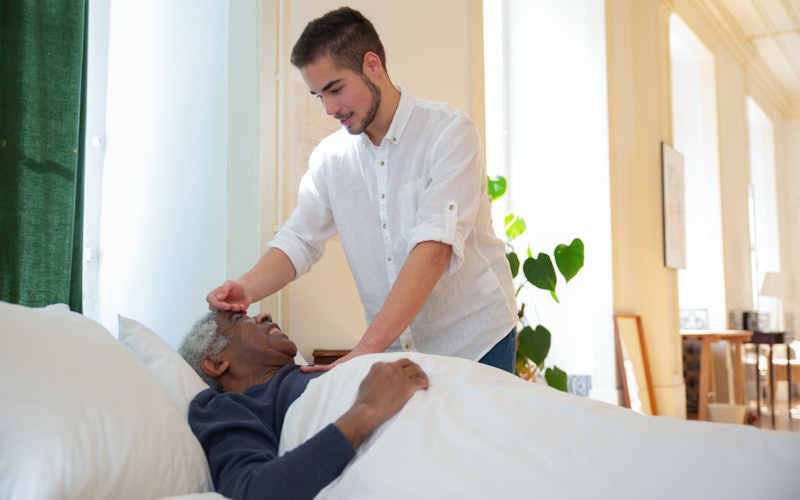 caretaker leaning over their patient in bed