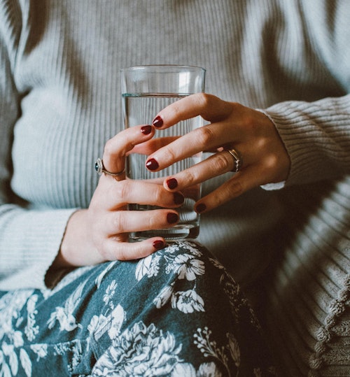 woman holding water glass on couch