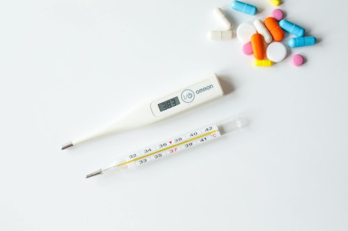 thermometers and pills on white counter