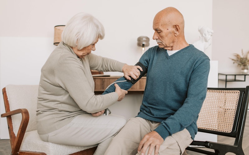 Elderly Woman Checking the Blood Pressure of an Elderly Man