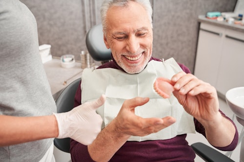 Dentist showing an older man his new dentures