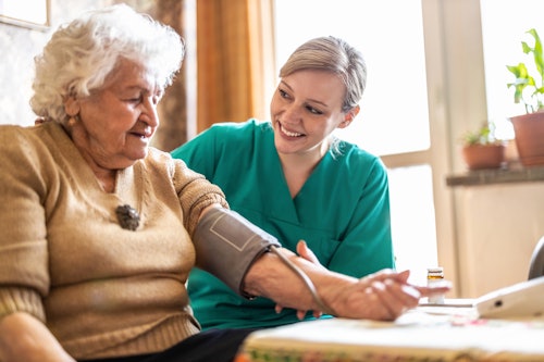 Smiling nurse checking an elderly womans blood pressure
