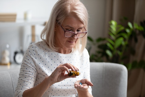 Woman sitting on couch holding medication pills
