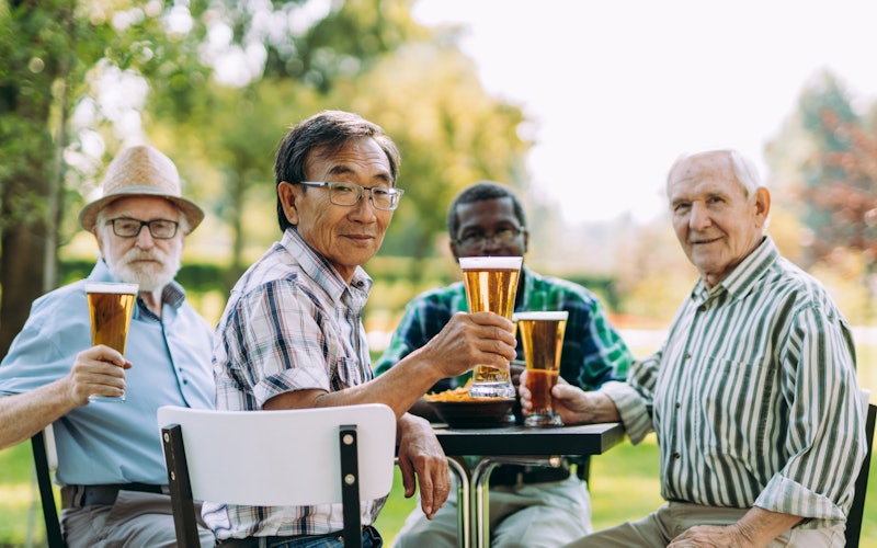 Group of older men drinking beer outdoors