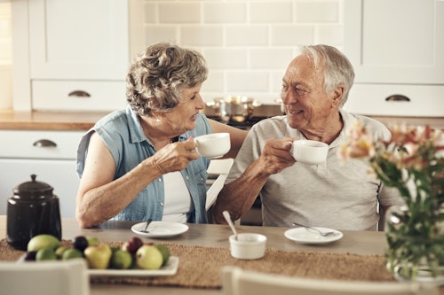 Happy elderly couple drinking coffee together in their kitchen