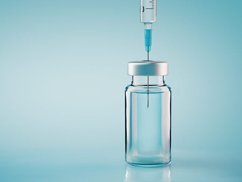 A close up of a syringe with its needle in a vial of liquid.
