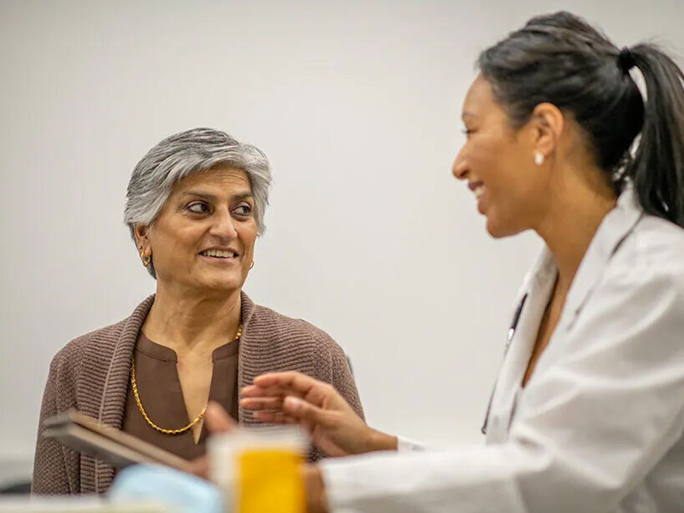A smiling doctor and patient sitting and looking at each.