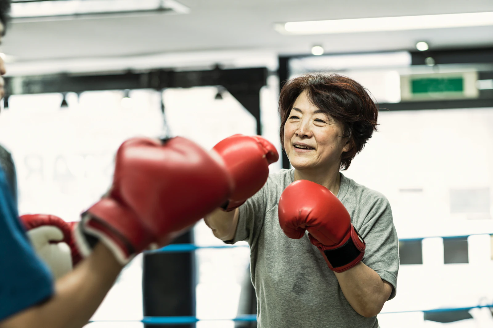 older woman boxing in gym with red gloves