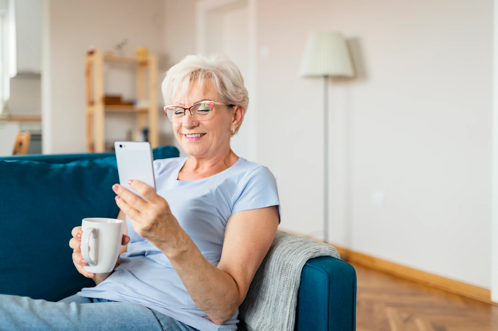 woman with phone and mug sitting on the couch