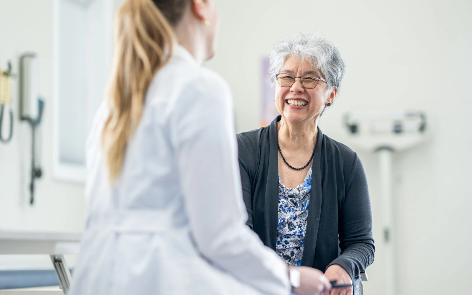 older woman patient on exam table talking with doctor