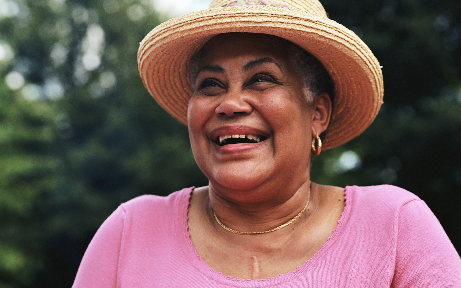 Woman smiling in pink shirt and sunhat