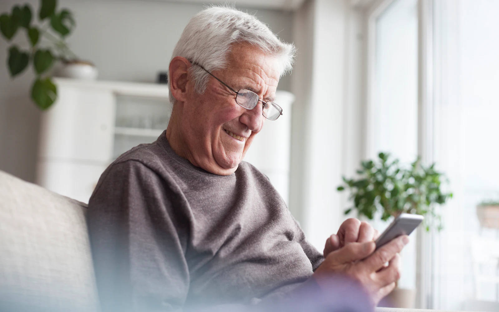 Man sitting on couch smiling at phone screen