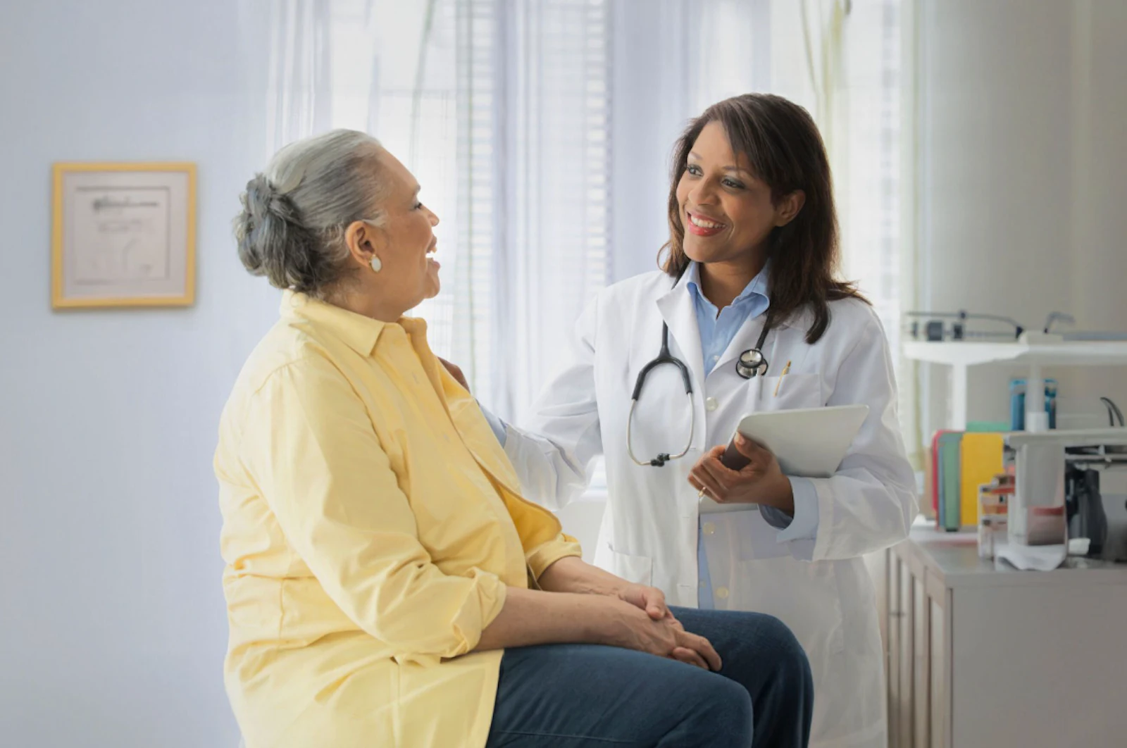 African American doctor with patient wearing yellow shirt in clinic