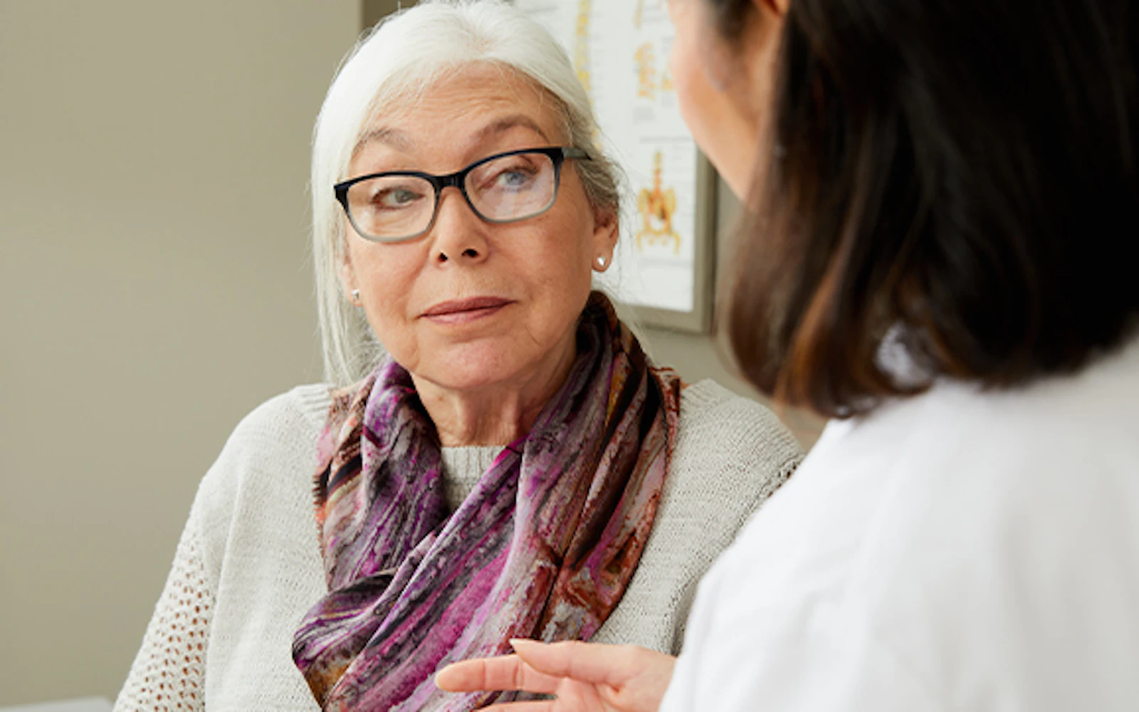A patient sits and listens while her physician talks.