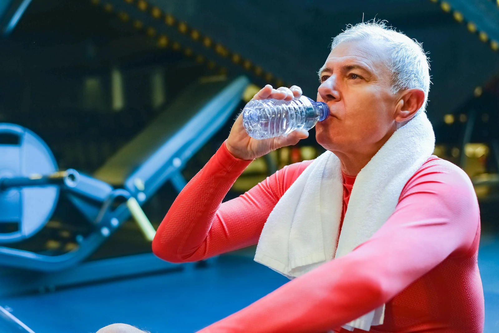 older man drinking water bottle in gym