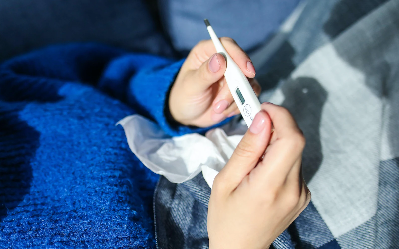 woman holding thermometer in blue sweater