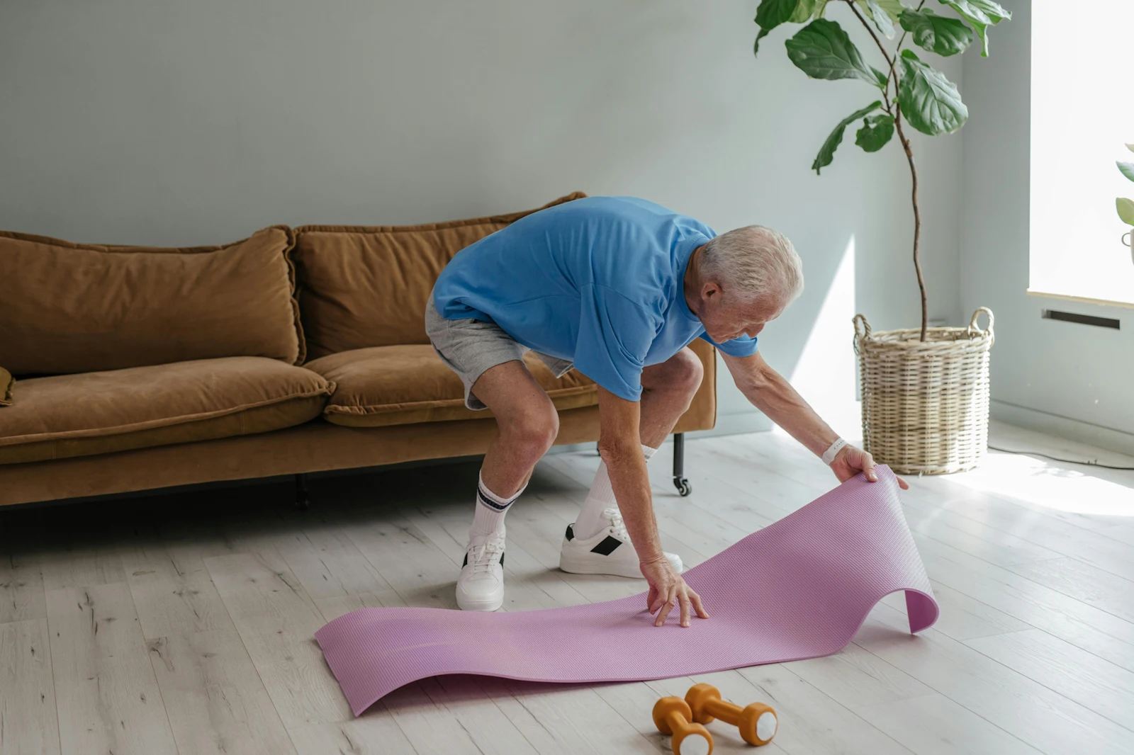 older man laying out yoga mat for exercise