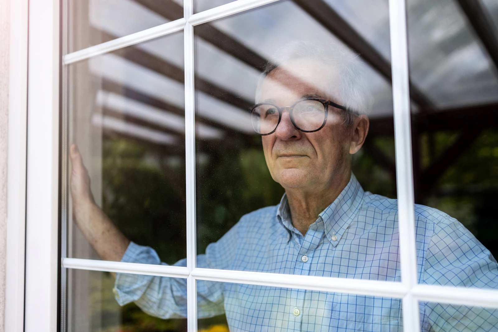 Older man looking out of the window at home