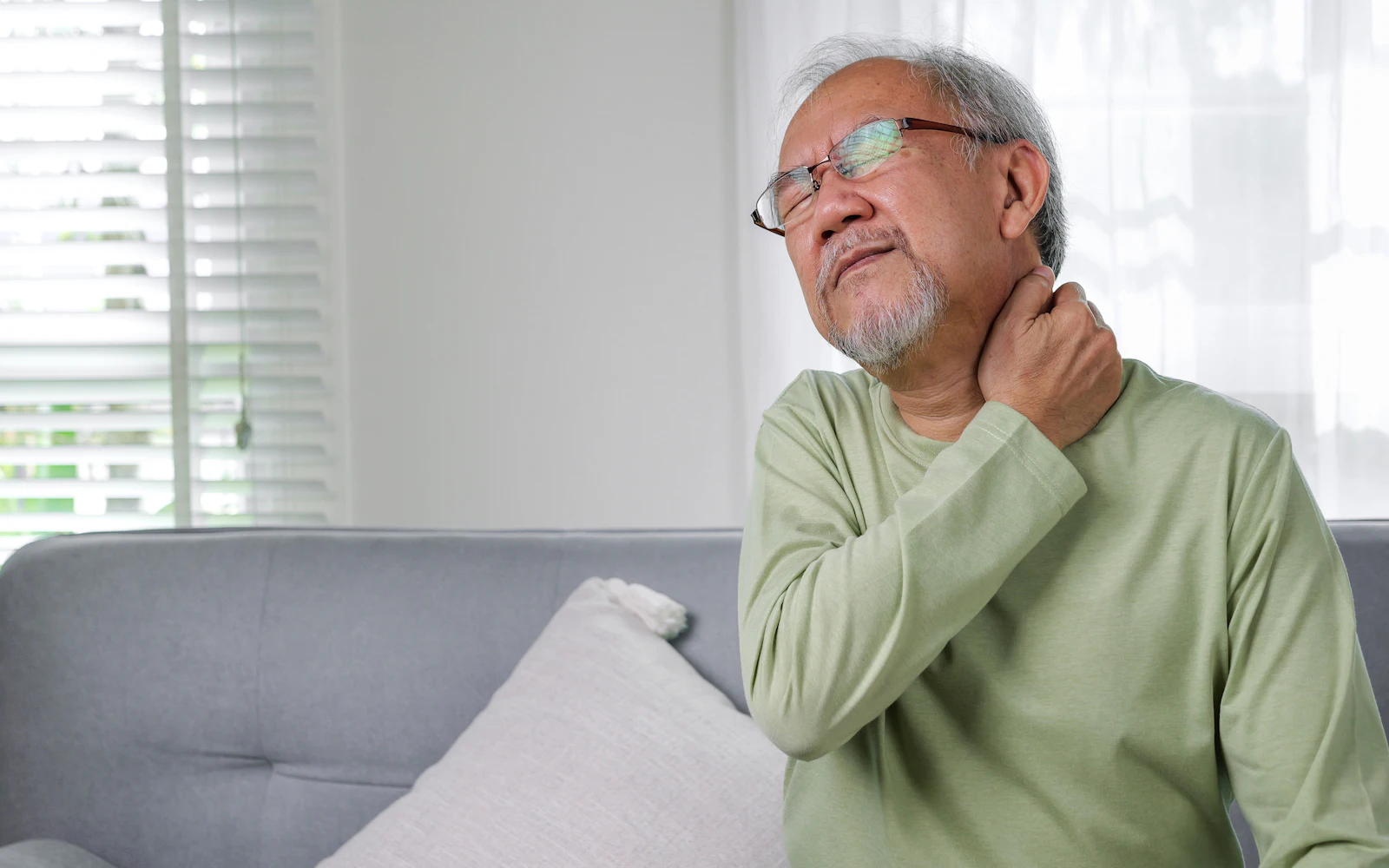 Older man holding his neck in discomfort