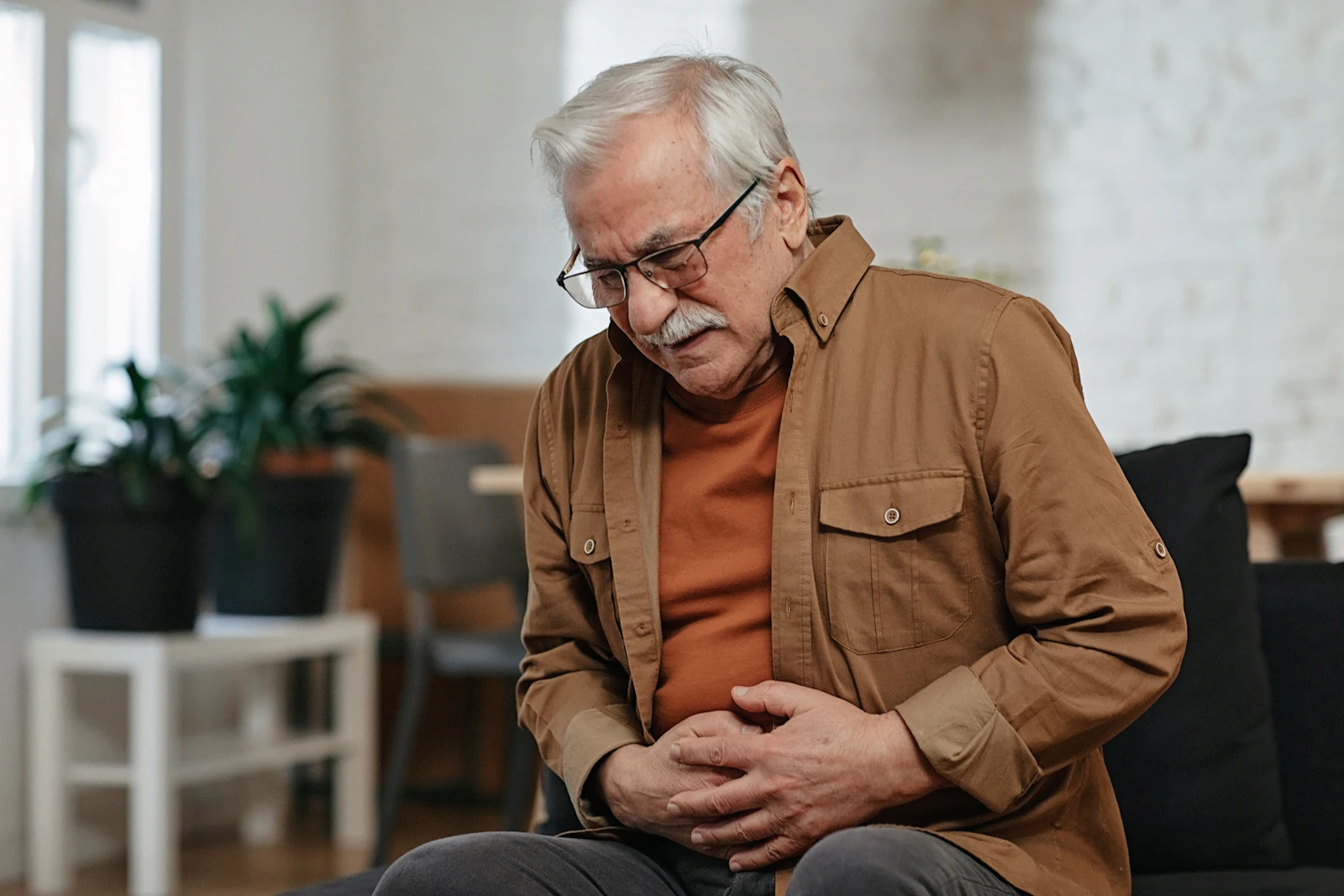 senior male bent over stomach in pain