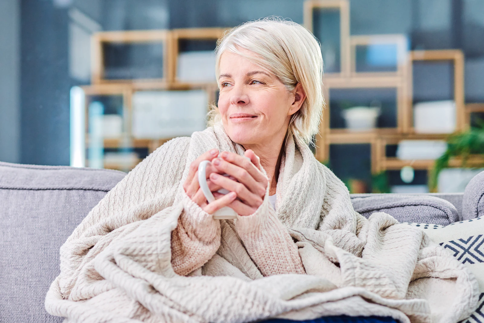 woman sitting with blanket and hot beverage